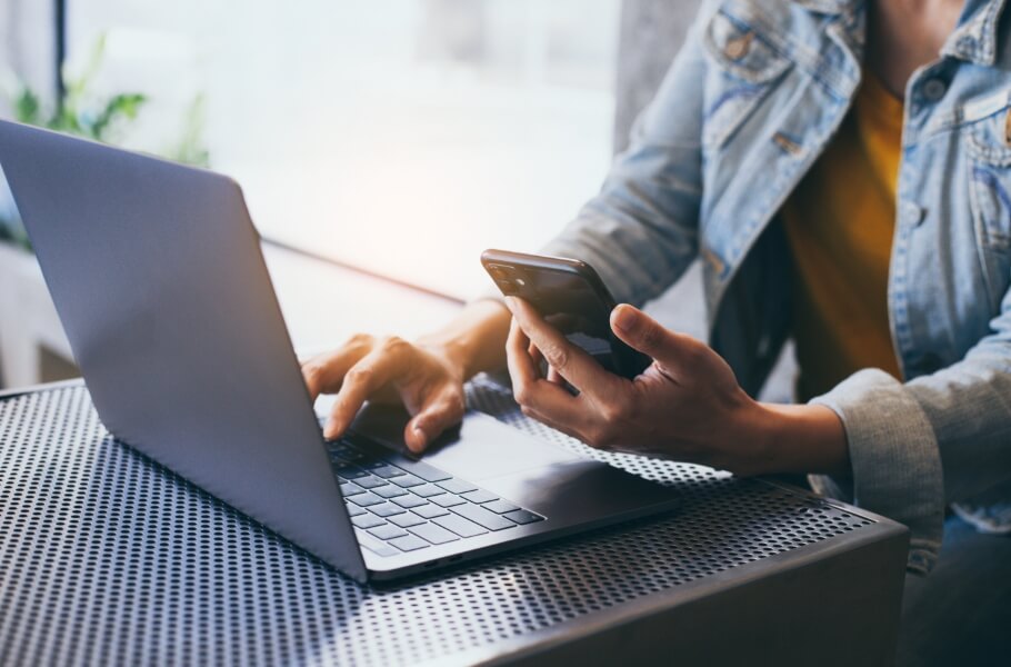 A person checking her phone while using laptop
