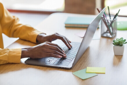 Person wearing yellow jacket using laptop